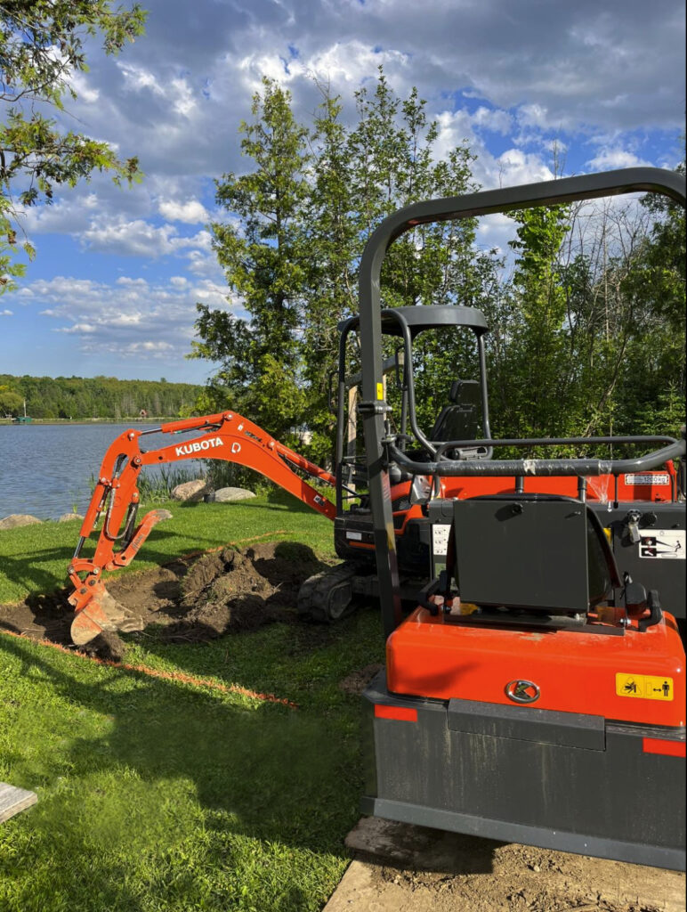 Bobcat excavating a hole by a lake